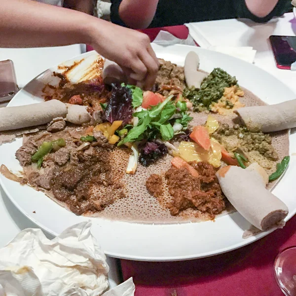 Etiyopya unu Injera ekmek ve çeşitli yemekler yemek eller