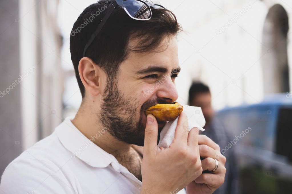 Handsome man eating a pastel de nata