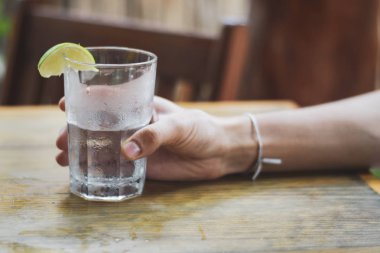 Erkek, su bardağını tutuyor.