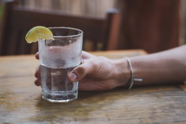 Erkek, su bardağını tutuyor.