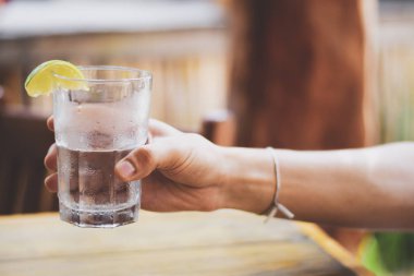 Erkek, su bardağını tutuyor.