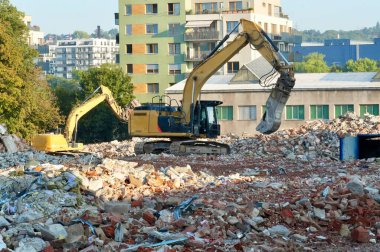 Önünde büyük bir kazıcı bulunan eski bir binanın yıkılması.