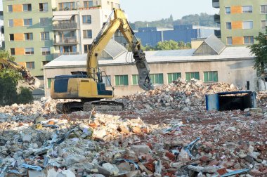 Çok katlı bir binanın yıkım alanında kazıcı.