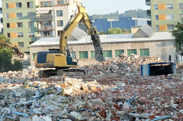 Çok katlı bir binanın yıkım alanında kazıcı.