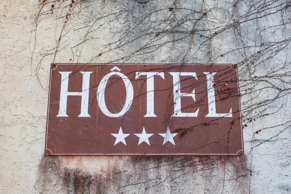 裸の木の小枝と灰色の壁に3つ星ホテルの看板のクローズアップ — ストック写真