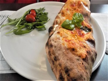 Napolice pizza, doldurulmuş, ahşap bir fırında pişmiş.