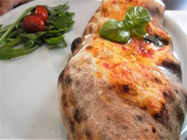 Napolice pizza, doldurulmuş, ahşap bir fırında pişmiş.