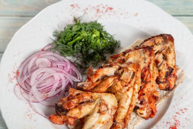 Kızarmış tavuk kanadı ile soğan ve yeşillik ahşap zemin üzerine tabak