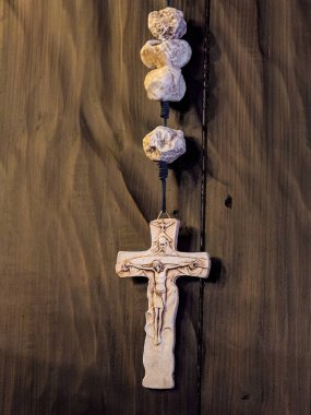 Ahşap bir duvarda asılı tespih ile taş çapraz. Closeup görünümü