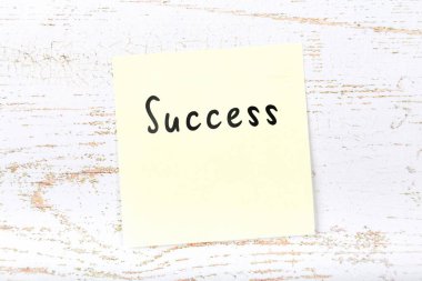 El yazısı metnini başarı ile ahşap masa üzerinde sarı yapışkan not