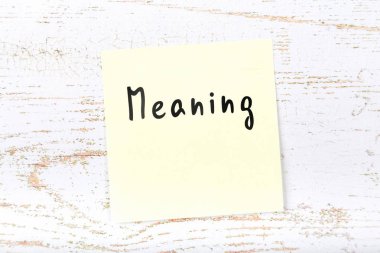 El yazısı metnini anlamı ile ahşap masa üzerinde sarı yapışkan not