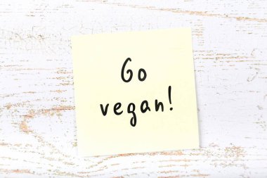 Sarı yapışkan not vegan ahşap masa el yazısı metin ile devam