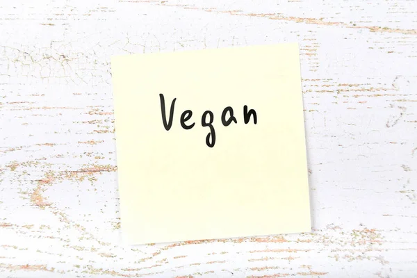 El yazısı metnini vegan ile ahşap masa üzerinde sarı yapışkan not