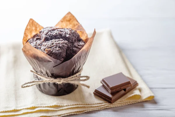 Handmade chocolate muffin with pieces of chocolate on wooden table with copy space