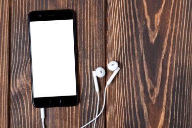 Ahşap arka plan üzerinde beyaz kulaklık ile Smartphone.