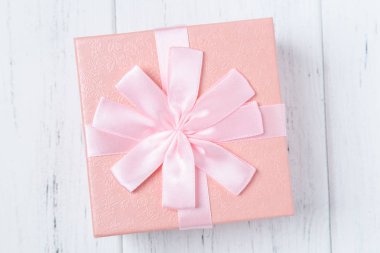Ahşap masa üzerinde yay ile dekoratif pembe hediye kutusu