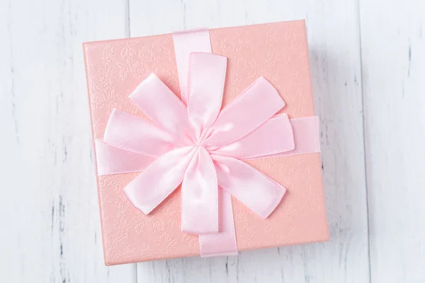Caja de regalo decorativa rosa con lazo en mesa de madera — Foto de Stock