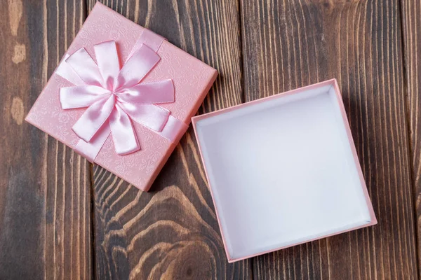 Vista superior de la caja de regalo rosa decorativa vacía abierta con arco en la mesa de madera marrón — Foto de Stock