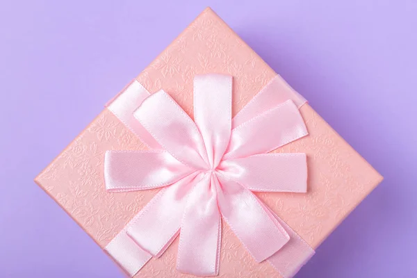 Caja de regalo decorativa rosa con lazo sobre fondo púrpura — Foto de Stock