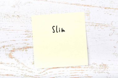 El yazısıyla yazılan kelime ince ile sarı yapışkan not