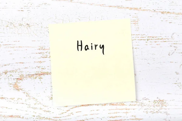 Yellow sticky note with handwritten word hairy — Stock Photo, Image