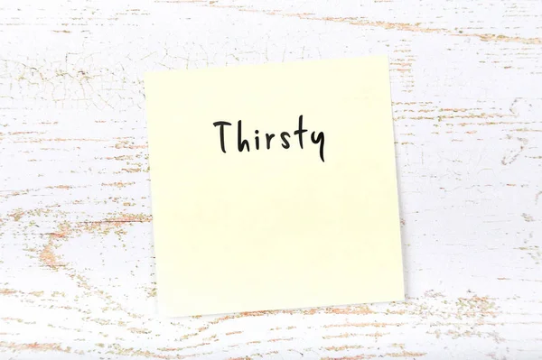 Yellow sticky note with handwritten word thirsty — Stock Photo, Image