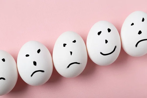 Concept of being unique. Hapyy smile on an egg among sad smiles.