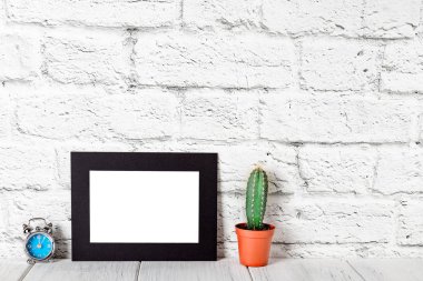 Duvara karşı beyaz tablo üzerinde siyah karton fotoğraf çerçevelemek. Mockup duvara karşı. Mockup
