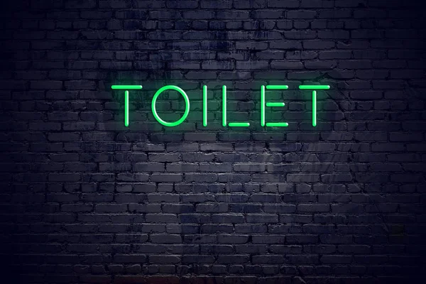 Bakstenen muur nachts met neon teken toilet — Stockfoto