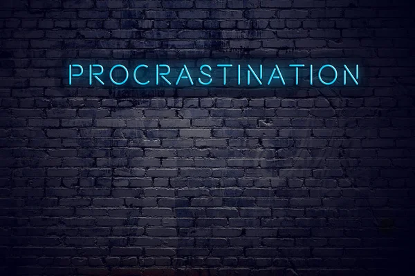 Parede de tijolo e sinal de néon com procrastinação de texto — Fotografia de Stock