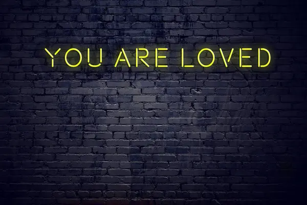 Positiv inspirerande citat på neonskylt mot tegelvägg du är älskad — Stockfoto