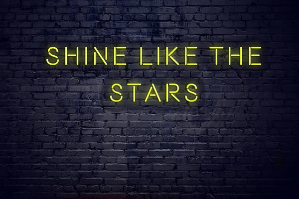 Positive inspiring quote on neon sign against brick wall shine like the stars