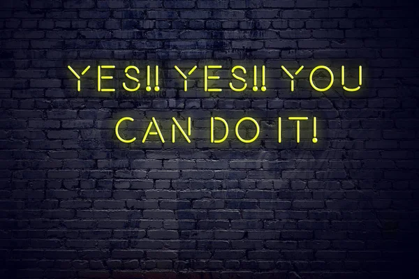 Positive inspiring quote on neon sign against brick wall yes yes you can do it