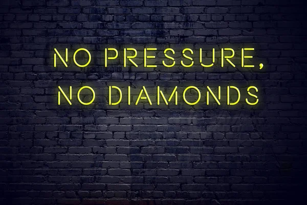 Positive inspiring quote on neon sign against brick wall no pressure no diamonds