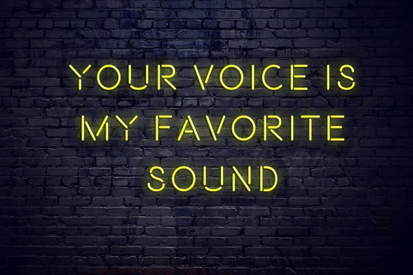 Positive inspiring quote on neon sign against brick wall your voice is my favorite sound