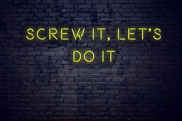 Positive inspiring quote on neon sign against brick wall screw it lets do it