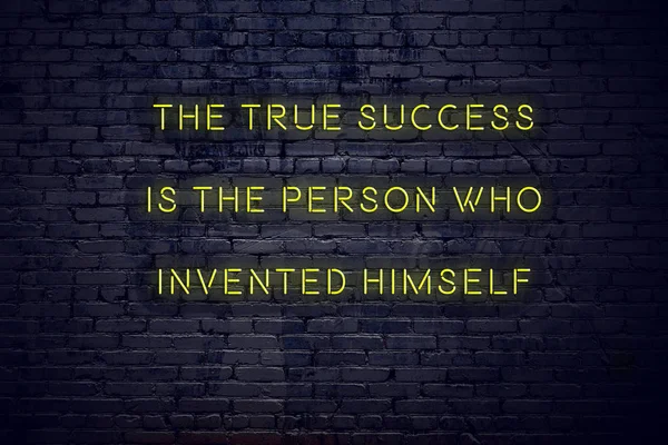 Positive inspiring quote on neon sign against brick wall the true success is the person who invented himself
