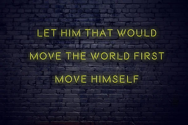 Positive inspiring quote on neon sign against brick wall let him that would move the world first move himself