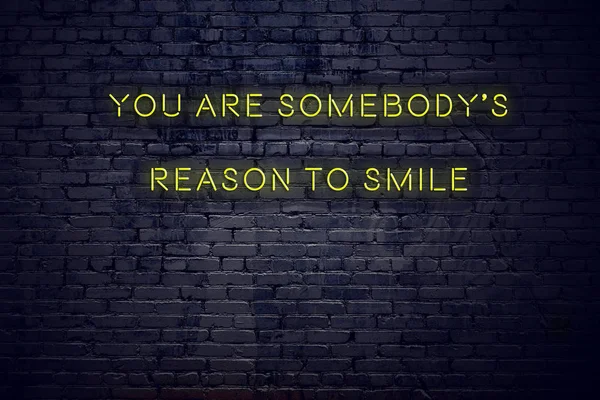 Positive inspiring quote on neon sign against brick wall you are somebodys reason to smile — Stock Photo, Image