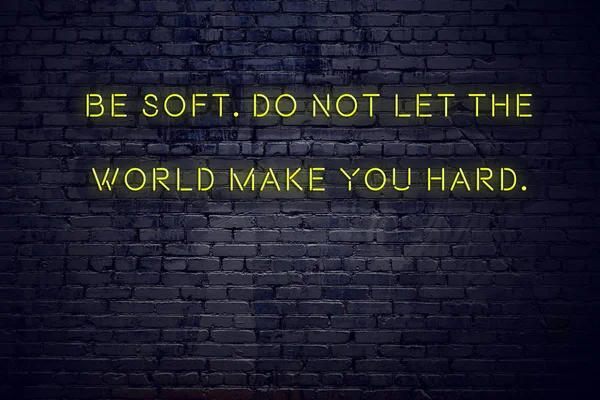 Positive inspiring quote on neon sign against brick wall be soft do not let the world make you hard
