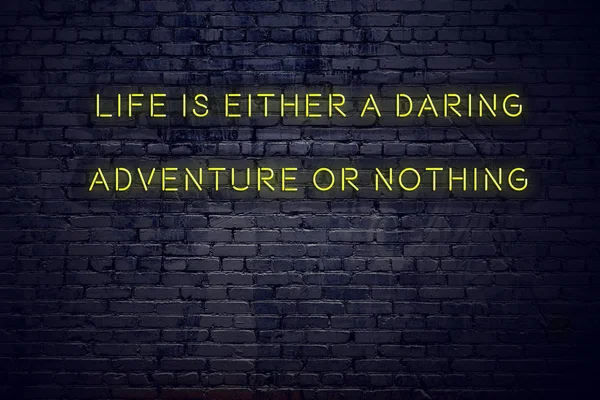 Positive inspiring quote on neon sign against brick wall life is either a daring adventure or nothing