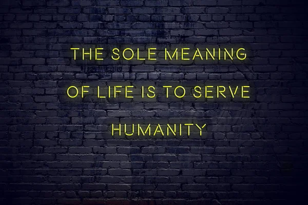 Positive inspiring quote on neon sign against brick wall the sole meaning of life is to serve humanity