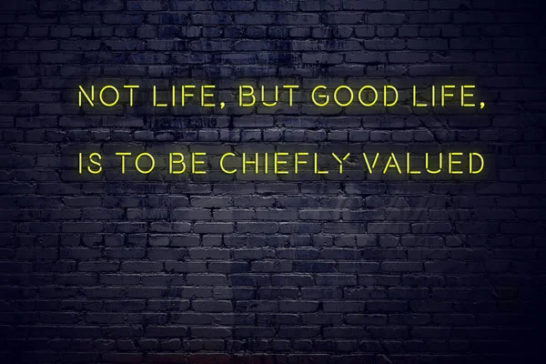Positive inspiring quote on neon sign against brick wall not life but good life is to be chiefly valued