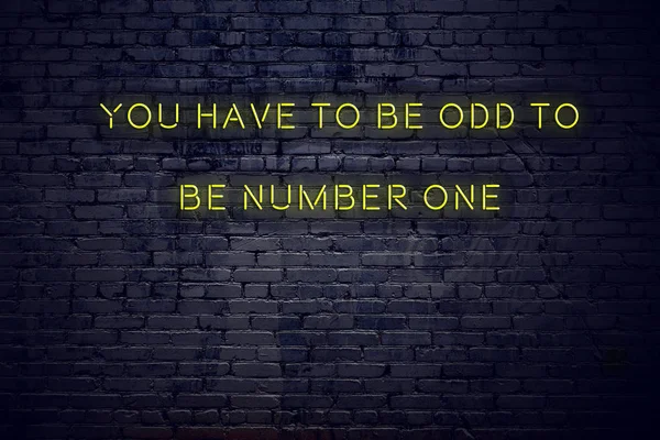 Positive inspiring quote on neon sign against brick wall you have to be odd to be number one