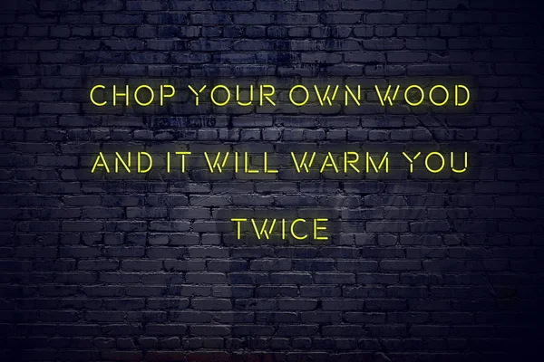 Positive inspiring quote on neon sign against brick wall chop your own wood and it will warm you twice