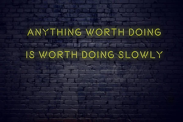 Positive inspiring quote on neon sign against brick wall anything worth doing is worth doing slowly — Stock Photo, Image