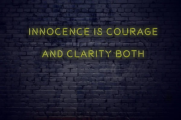 Positive inspiring quote on neon sign against brick wall innocence is courage and clarity both