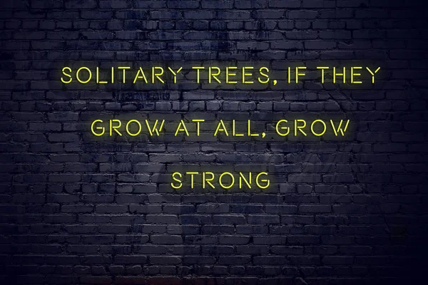 Positive inspiring quote on neon sign against brick wall solitary trees if they grow at all grow strong — Stock Photo, Image