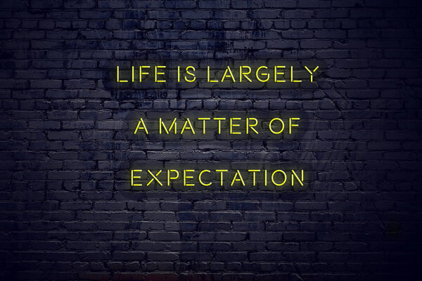 Positive inspiring quote on neon sign against brick wall life is largely a matter of expectation