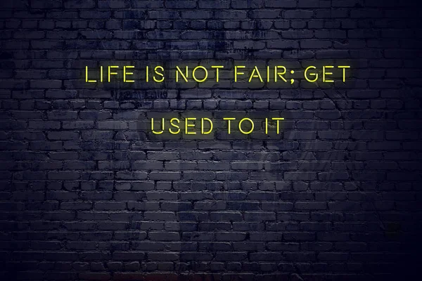 Positive inspiring quote on neon sign against brick wall life is not fair get used to it